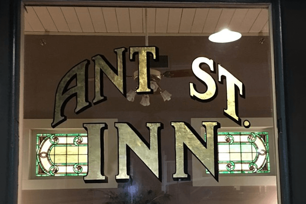 Sign for "ANT ST. INN" with decorative stained glass windows in the background.